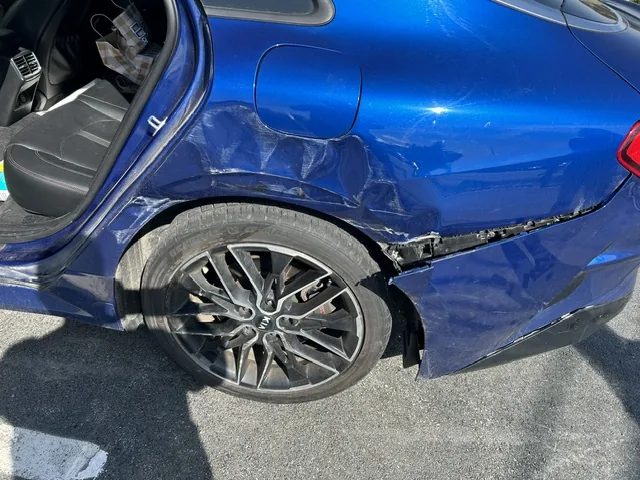 Collision damage to the rear quarter panel of a blue sedan