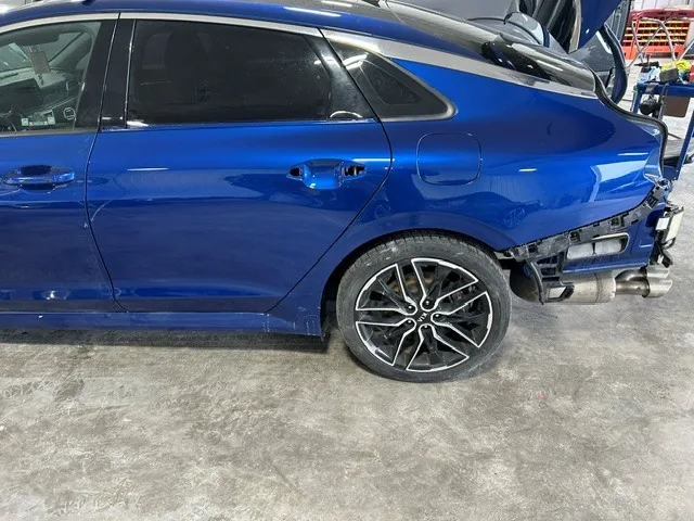 Blue sedan with rear-end collision damage in the shop